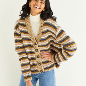 Woman smiling in a chunky multicolored striped cardigan over a cream turtleneck and blue jeans.