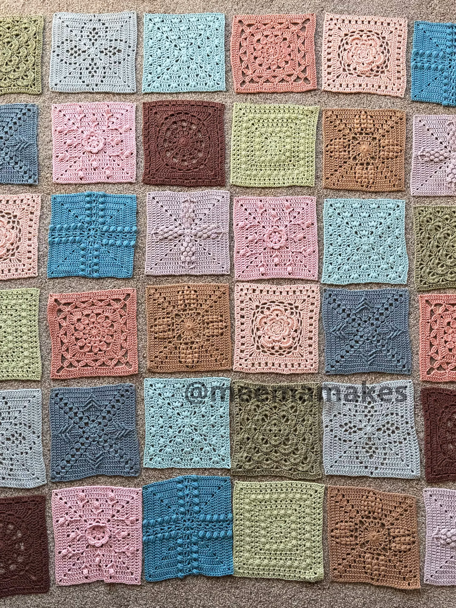 2d1df7e4-c94c-4403-8d43-9b2569f3121a Colorful crocheted granny squares laid out on a beige carpet, forming a grid of pastel tones.