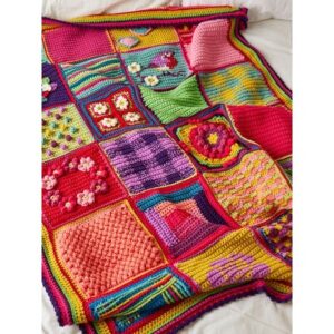 Colorful crochet patchwork blanket with many square patches featuring flowers and stripes laid on a white bed.