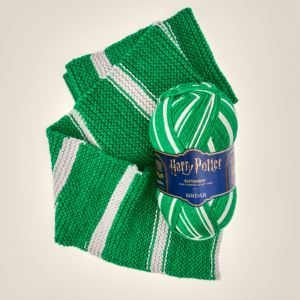 Green knitted scarf with white stripes, wrapped around a blue Harry Potter yarn label and skein of yarn.